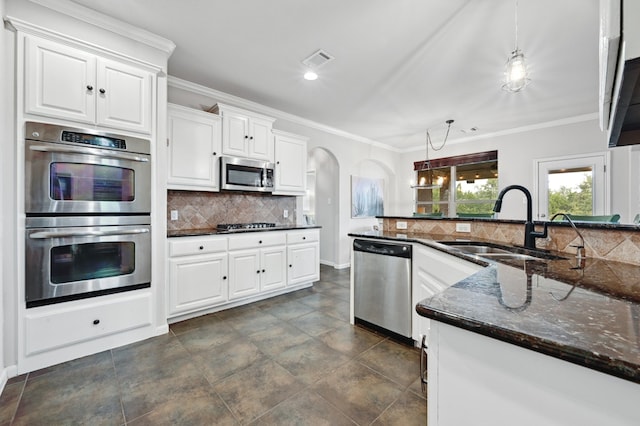 kitchen featuring visible vents, arched walkways, ornamental molding, appliances with stainless steel finishes, and decorative backsplash