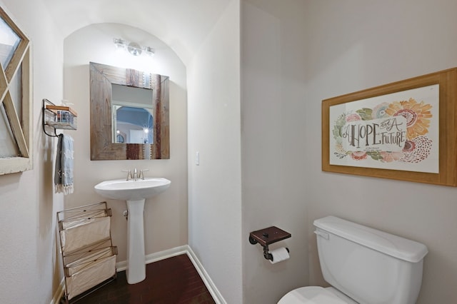 bathroom with toilet, baseboards, and wood finished floors
