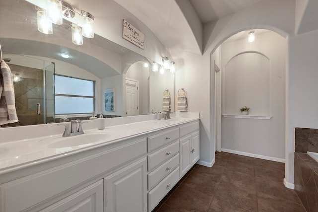 full bath featuring a shower stall, tile patterned flooring, a sink, double vanity, and baseboards