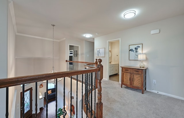 hallway featuring an upstairs landing, baseboards, crown molding, and carpet floors
