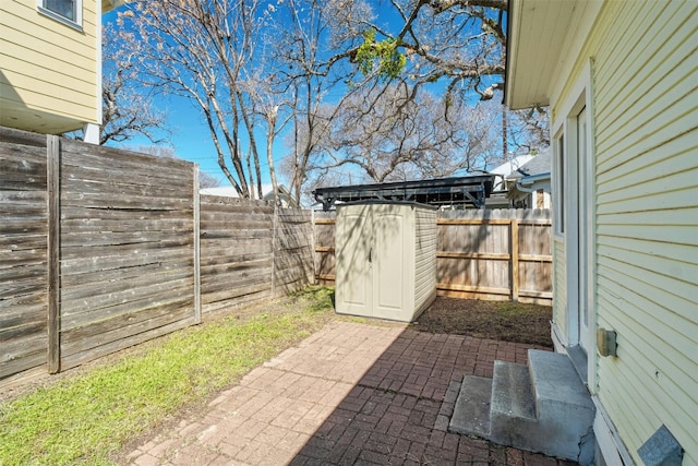 view of patio with a storage shed, a fenced backyard, and an outbuilding