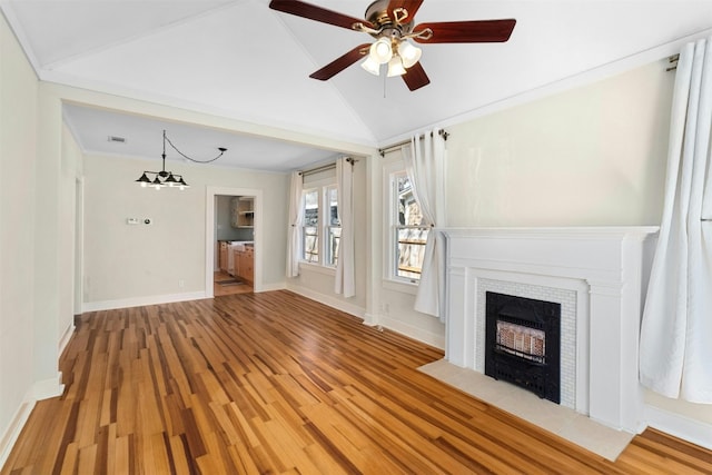 unfurnished living room with a tile fireplace, lofted ceiling, baseboards, and wood finished floors