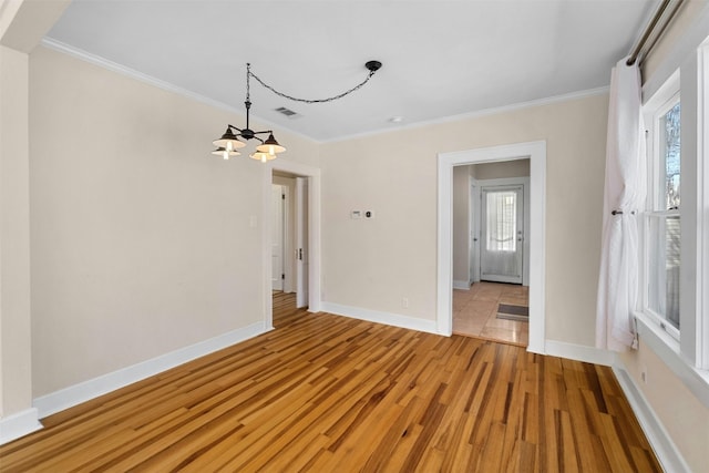 spare room featuring crown molding, plenty of natural light, baseboards, and light wood-style floors