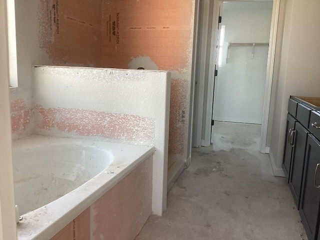 full bathroom with a bath and unfinished concrete flooring