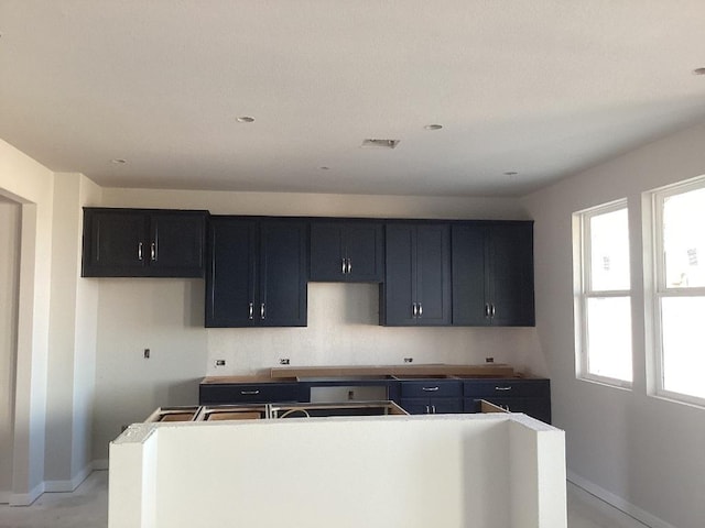 kitchen with tasteful backsplash, baseboards, visible vents, a kitchen island, and dark cabinets