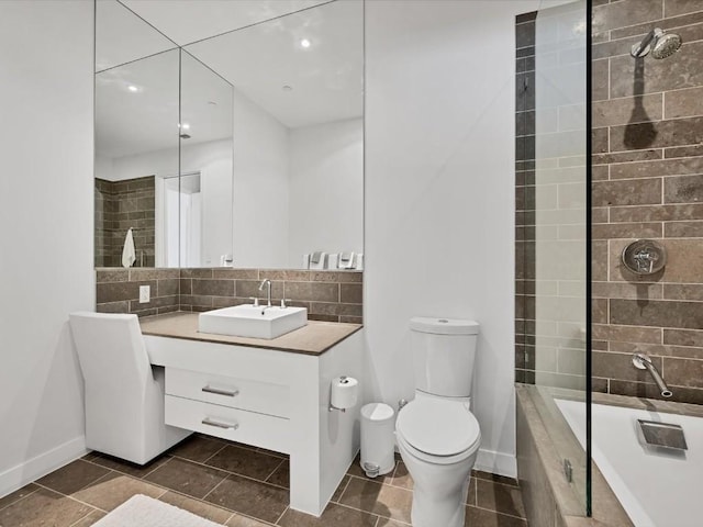 bathroom featuring toilet, vanity, baseboards, tiled shower / bath, and decorative backsplash