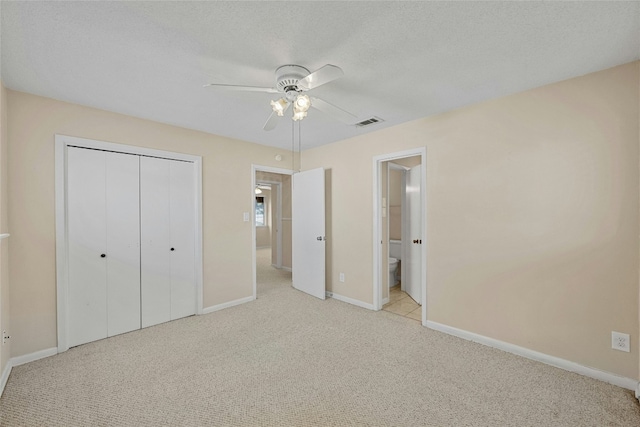 unfurnished bedroom with a textured ceiling, light carpet, visible vents, baseboards, and a closet