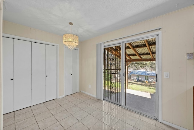 interior space with an inviting chandelier, a textured ceiling, and light tile patterned flooring