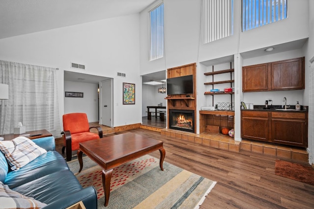 living room with a healthy amount of sunlight, a warm lit fireplace, visible vents, and wood finished floors