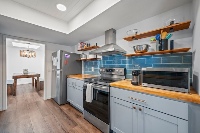 kitchen with stainless steel appliances, butcher block countertops, decorative backsplash, open shelves, and island exhaust hood