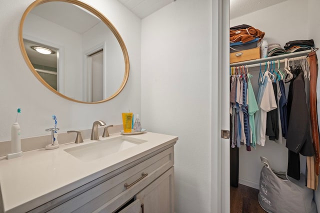 bathroom with a spacious closet, wood finished floors, and vanity