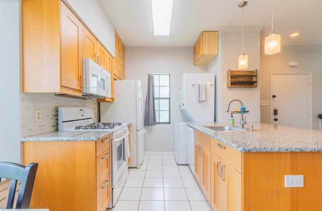 kitchen featuring light stone countertops, white appliances, a sink, and decorative light fixtures