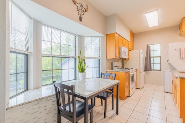 kitchen with white appliances, plenty of natural light, light countertops, and light tile patterned flooring