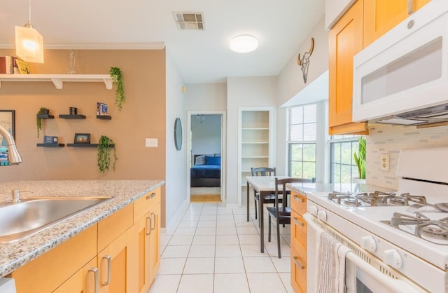 kitchen featuring light tile patterned flooring, white appliances, a sink, visible vents, and pendant lighting