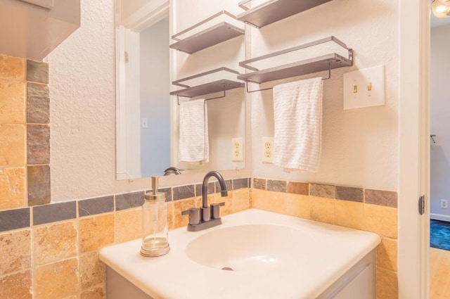 bathroom with a textured wall, tile walls, and vanity