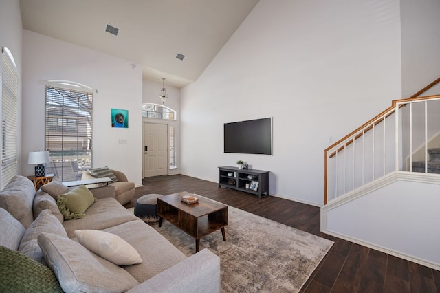 living area with high vaulted ceiling, dark wood-style flooring, visible vents, and stairs