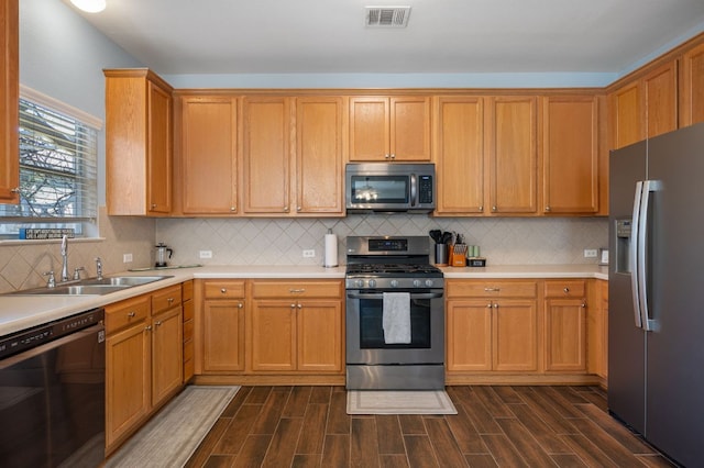 kitchen featuring appliances with stainless steel finishes, wood tiled floor, visible vents, and a sink