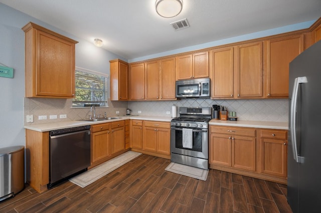 kitchen with stainless steel appliances, light countertops, visible vents, wood tiled floor, and a sink