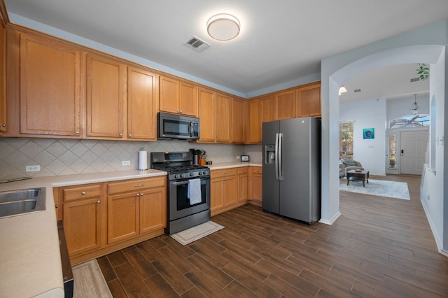 kitchen featuring stainless steel appliances, visible vents, light countertops, backsplash, and dark wood finished floors