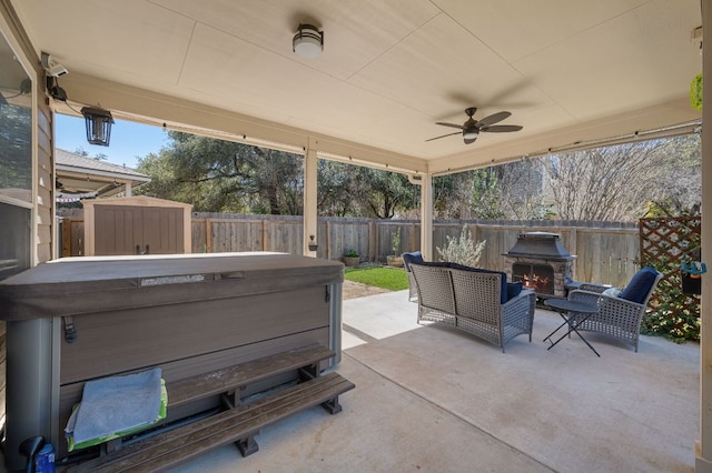 view of patio / terrace featuring a storage shed, a hot tub, ceiling fan, a fenced backyard, and an outdoor structure