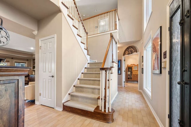 entryway with stairs, a high ceiling, baseboards, and wood finished floors