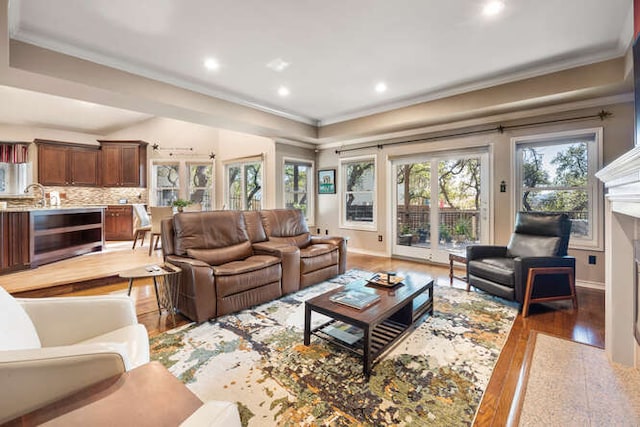 living room featuring light wood-style flooring, recessed lighting, beverage cooler, a high end fireplace, and crown molding