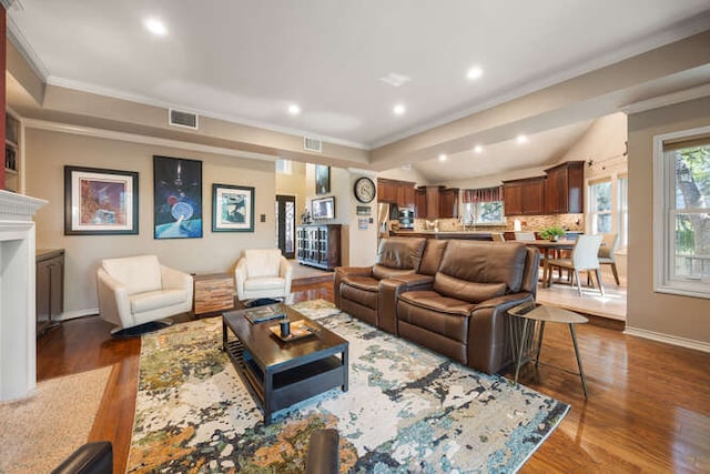 living area featuring crown molding, a fireplace, visible vents, and dark wood-type flooring