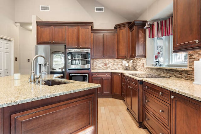 kitchen featuring light stone counters, visible vents, vaulted ceiling, and a sink