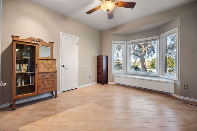 interior space featuring light wood-type flooring, a baseboard heating unit, baseboards, and a ceiling fan