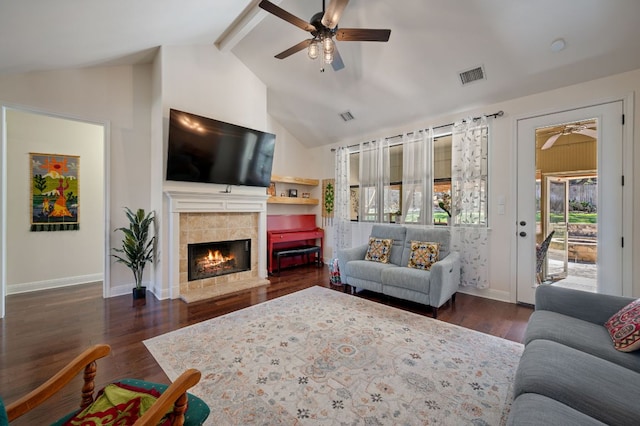 living room featuring lofted ceiling with beams, visible vents, dark wood-type flooring, and a tile fireplace