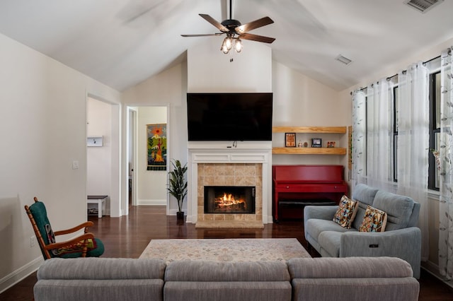 living area featuring a tile fireplace, dark wood-style flooring, visible vents, and vaulted ceiling