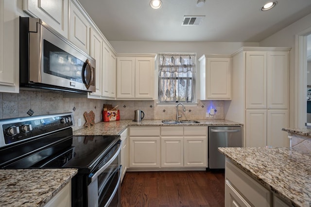 kitchen featuring a sink, visible vents, appliances with stainless steel finishes, dark wood-style floors, and tasteful backsplash