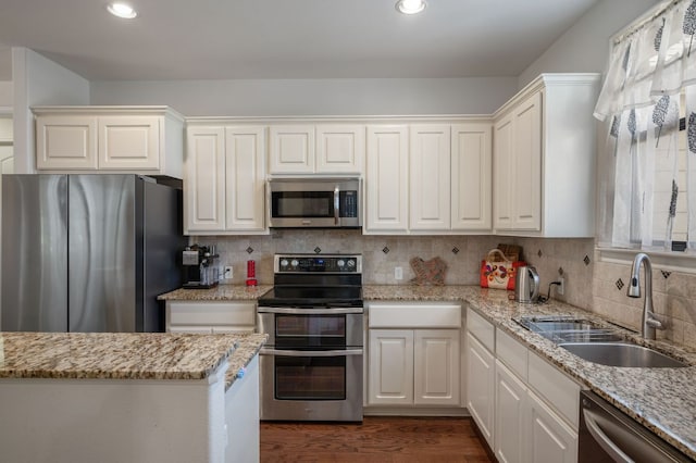 kitchen featuring light stone counters, decorative backsplash, stainless steel appliances, and a sink