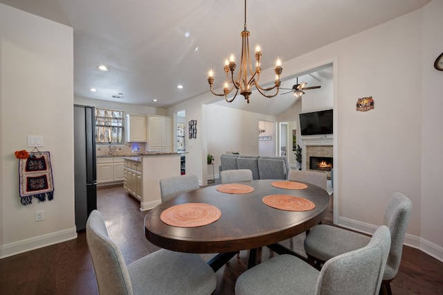 dining space with vaulted ceiling, a fireplace, dark wood finished floors, and baseboards