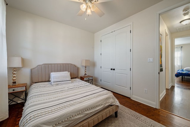 bedroom with wood finished floors, a ceiling fan, visible vents, baseboards, and a closet