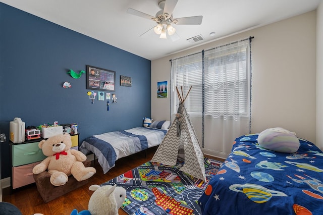 bedroom with ceiling fan, visible vents, and wood finished floors