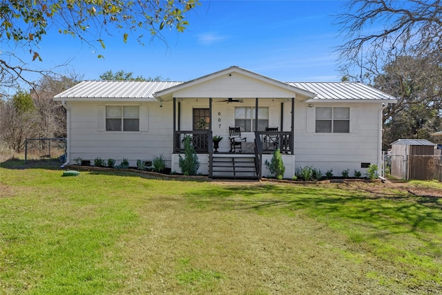 view of front facade featuring metal roof, covered porch, fence, a ceiling fan, and a front yard