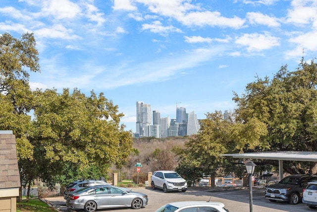 partially covered parking lot featuring a view of city and fence