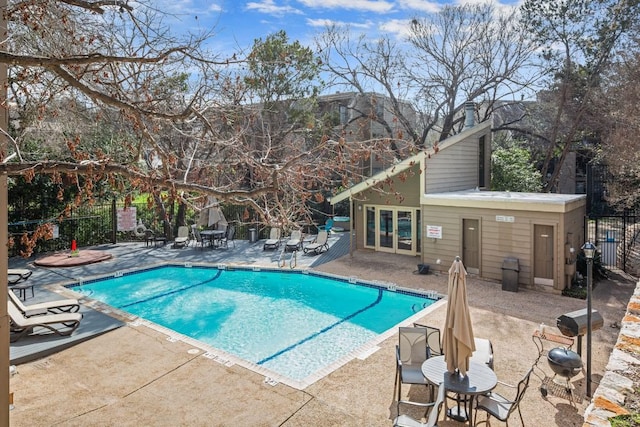 community pool featuring a patio area, fence, and french doors