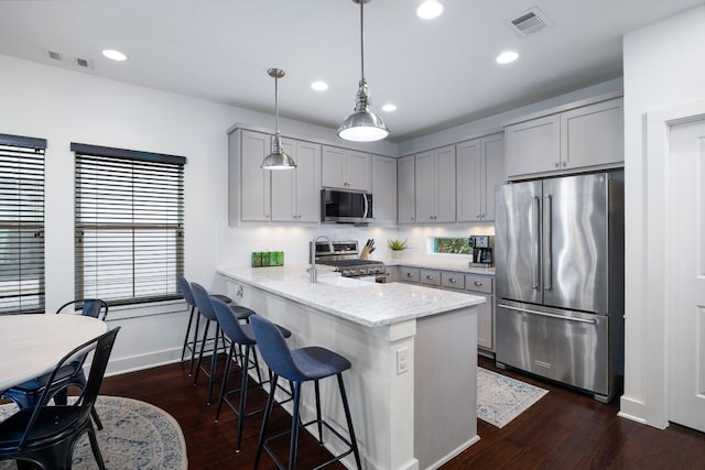 kitchen with light stone counters, visible vents, hanging light fixtures, appliances with stainless steel finishes, and a peninsula