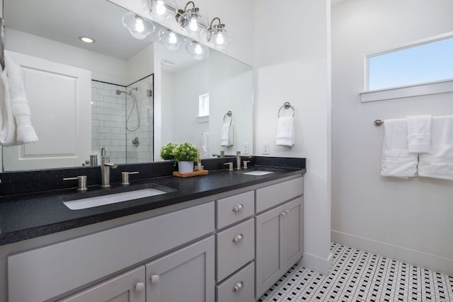 full bath with a stall shower, a sink, baseboards, and double vanity