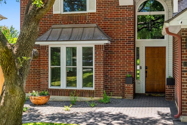 entrance to property with a standing seam roof, metal roof, and brick siding