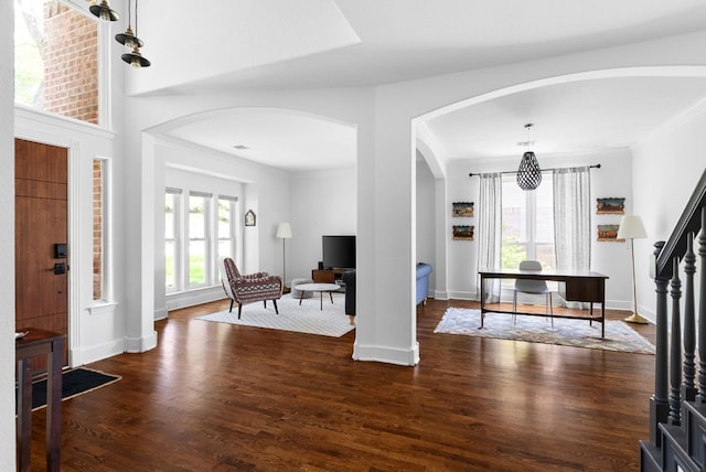 entrance foyer featuring baseboards, arched walkways, dark wood finished floors, and a wealth of natural light