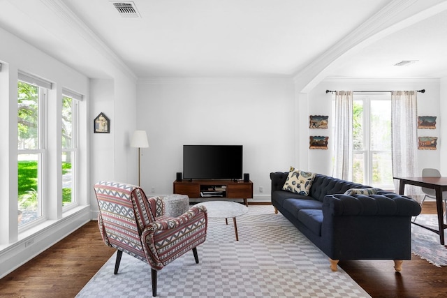 living area with baseboards, crown molding, visible vents, and wood finished floors