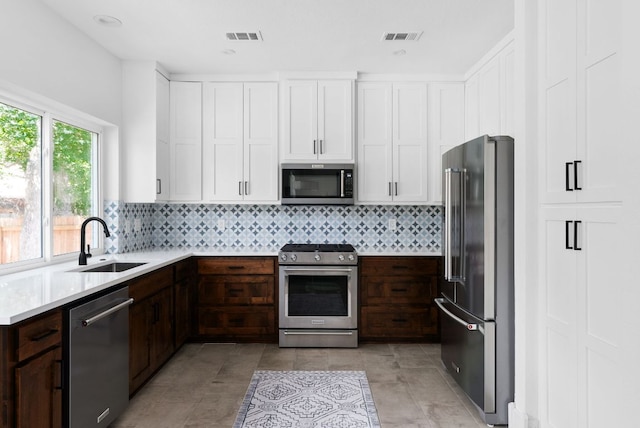 kitchen featuring stainless steel appliances, light countertops, visible vents, white cabinets, and a sink