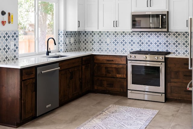 kitchen featuring backsplash, appliances with stainless steel finishes, light countertops, and a sink