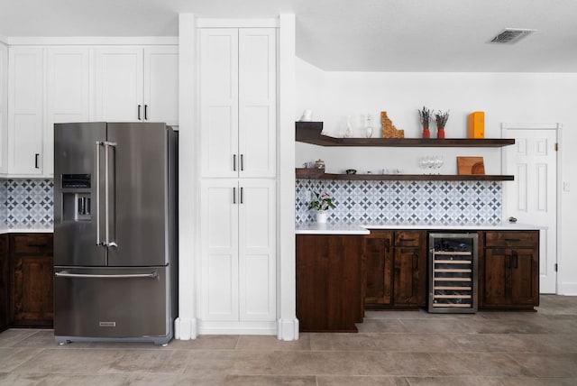 interior space with beverage cooler, visible vents, high quality fridge, a bar, and backsplash