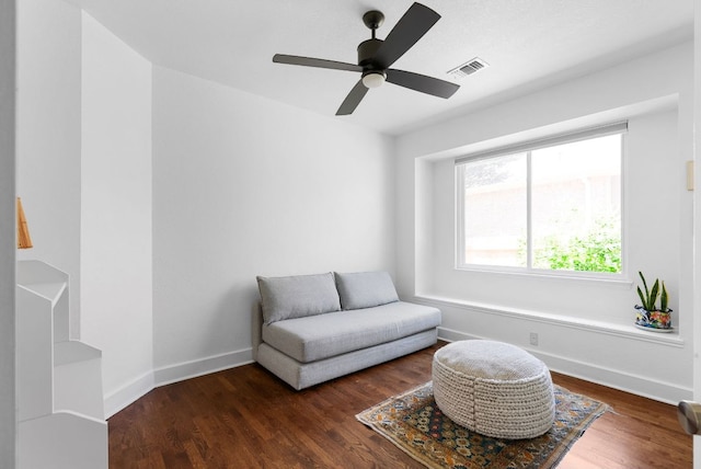 sitting room featuring a ceiling fan, dark wood finished floors, visible vents, and baseboards