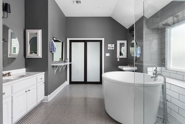 bathroom with baseboards, visible vents, vaulted ceiling, vanity, and a freestanding tub