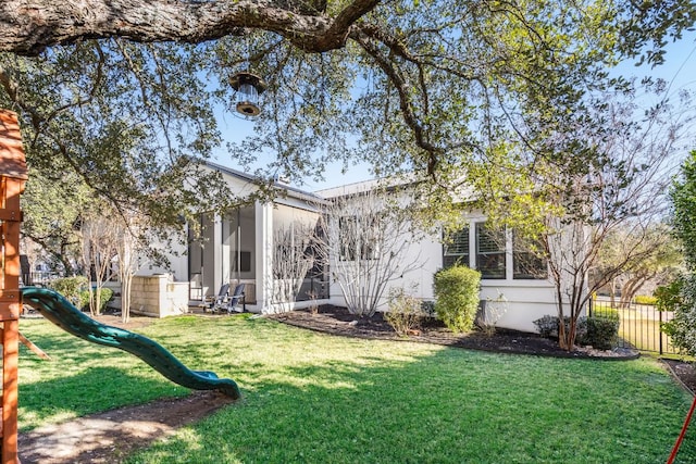 back of house with a lawn, a playground, and fence